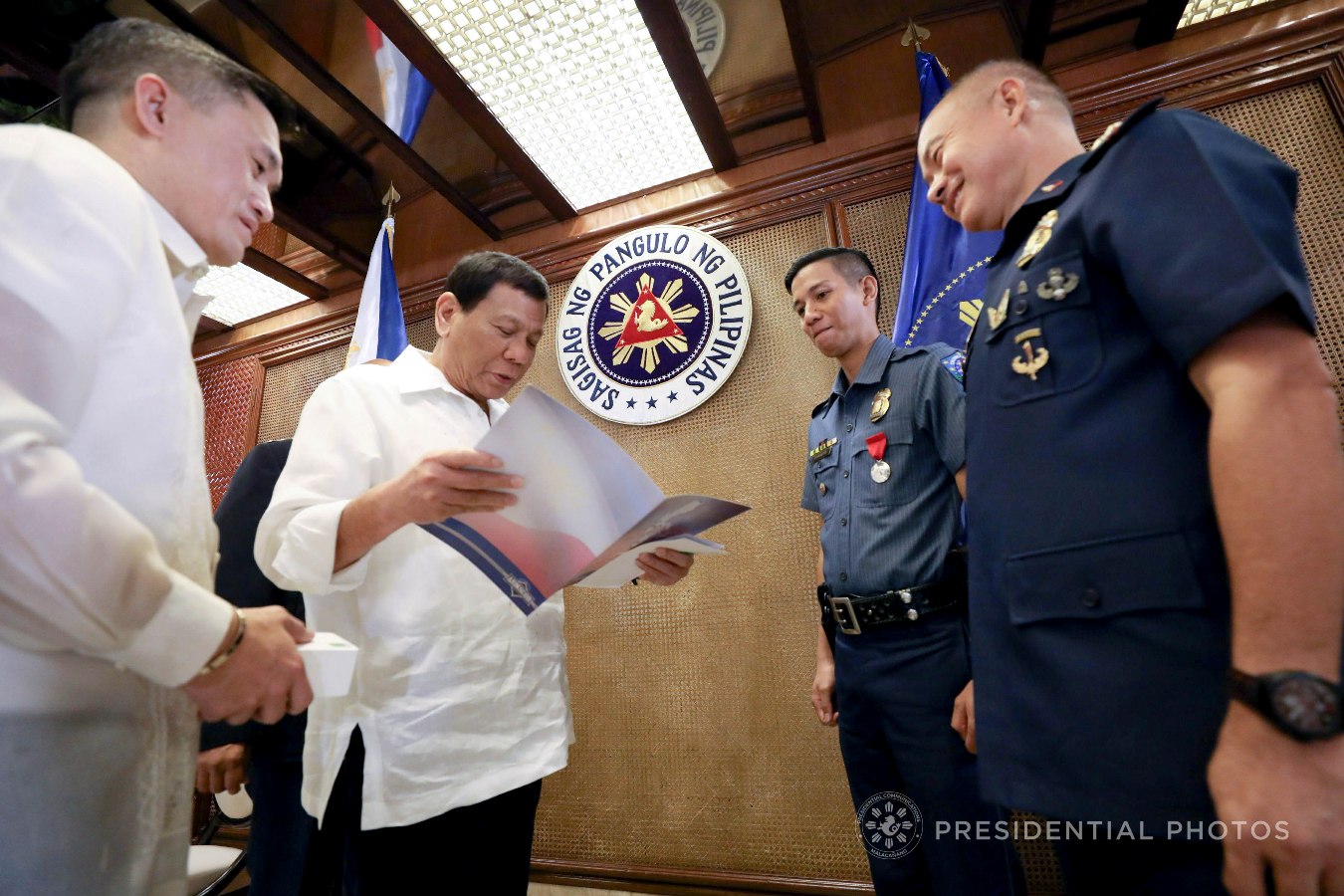 President Rodrigo Roa Duterte reads the brochure of the firearm that he is set to give to Order of Lapu-Lapu, Kampilan Medal awardee PO1 Ronald Anicete on the sidelines of the Joint Armed Forces of the Philippines (AFP)-Philippine National Police (PNP) Command Conference in Malacañan Palace on November 6, 2017. Anicete was stabbed by a man who resisted arrest in Caloocan City sometime in September. Also in the photo are Special Assistant to the President Christopher Lawrence Go and National Captial Region Police Office Direcor Oscar Albayalde. KARL NORMAN ALONZO/PRESIDENTIAL PHOTO