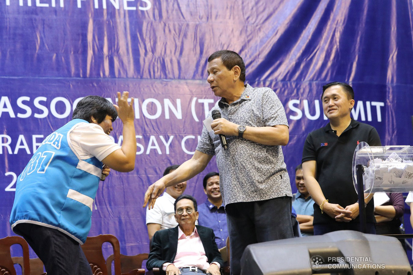 President Rodrigo Roa Duterte enjoys a light moment with one of the raffle draw winners during the Tricycle Operators and Drivers’ Association (TODA) Summit at the Cuneta Astrodome in Pasay City on January 23, 2019. Also in the photo is Presidential Spokesperson and Chief Legal Counsel Salvador Panelo, Social and Welfare Development Secretary Rolando Bautista, and Former Special Assistant to the President Christopher Lawrence "Bong" Go who were among the invited guests during the event. REY BANIQUET/PRESIDENTIAL PHOTO