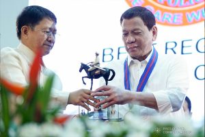 President Rodrigo Roa Duterte is assisted by Interior and Local Government Secretary Eduardo Año as he hands over a trophy to one of the awardees during the 118th Police Service Anniversary at Camp Brigadier General Rafael T. Crame in Quezon City on August 9, 2019. KING RODRIGUEZ/PRESIDENTIAL PHOTO