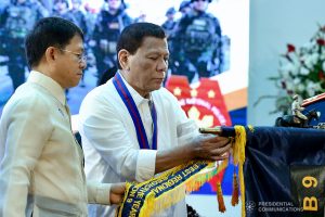President Rodrigo Roa Duterte attaches the streamer on the banner of one of the award-winning Philippine National Police (PNP) Units during the 118th Police Service Anniversary at Camp Brigadier General Rafael T. Crame in Quezon City on August 9, 2019. Assisting the President is Interior and Local Government Secretary Eduardo Año. RICHARD MADELO/PRESIDENTIAL PHOTO