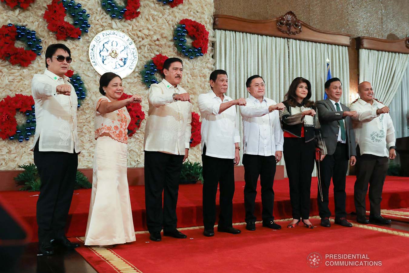 President Rodrigo Roa Duterte strikes his signature pose with Senators Ramon Revilla Jr., Cynthia Villar, Vicente Sotto III, Christopher "Bong" Go, Imee Marcos, Francis Tolentino and Ronald dela Rosa during the ceremonial signing of the Postponement of the 2020 Barangay and Sangguniang Kabataan Elections Act and the Malasakit Center Act at the Malacañan Palace on December 3, 2019. TOTO LOZANO/PRESIDENTIAL PHOTO