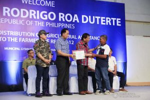 President Rodrigo Roa Duterte shares a light moment with one of the recipients of agricultural assistance during the ceremonial distribution at the Pigcawayan Municipal Gymnasium in Cotabato on January 10, 2020. Also in the photo are Senator Christopher "Bong" Go and Agriculture Secretary William Dar. ROBINSON NIÑAL JR./PRESIDENTIAL PHOTO