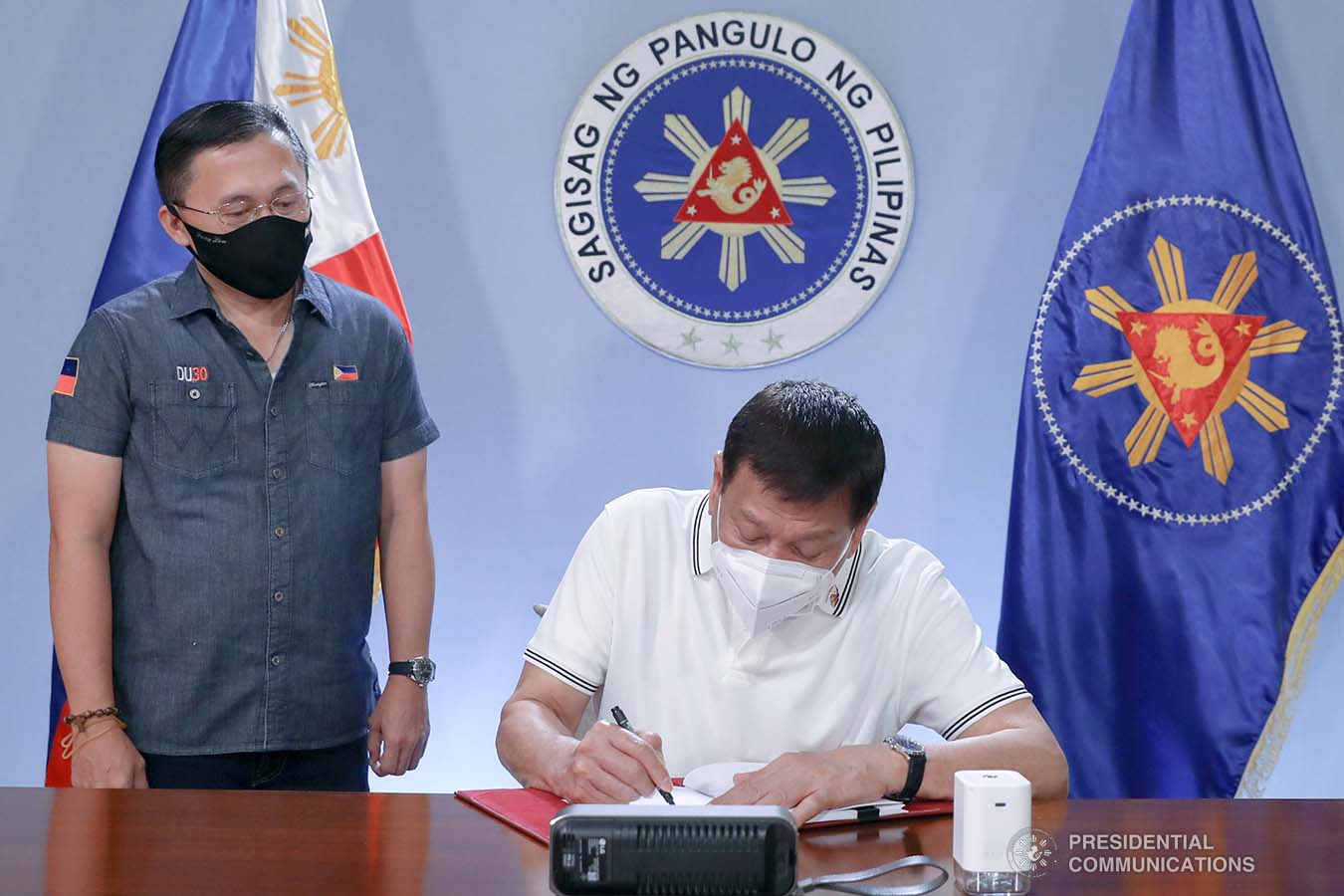 President Rodrigo Roa Duterte signs into law the Coronavirus Disease 2019 (COVID-19) Vaccination Program Act of 2021 at the Malacañang Golf (Malago) Clubhouse in Malacañang Park, Manila on February 26, 2021. The said law would expedite the procurement and administration of vaccines for the protection against COVID-19. It also covers the creation of an indemnity fund to cover compensation for those who would experience serious adverse effects to the vaccine. The President is accompanied by Senator Christopher Lawrence Go. KARL NORMAN ALONZO/ PRESIDENTIAL PHOTO