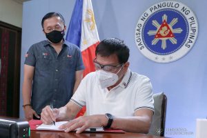 President Rodrigo Roa Duterte signs into law the Coronavirus Disease 2019 (COVID-19) Vaccination Program Act of 2021 at the Malacañang Golf (Malago) Clubhouse in Malacañang Park, Manila on February 26, 2021. The said law would expedite the procurement and administration of vaccines for the protection against COVID-19. It also covers the creation of an indemnity fund to cover compensation for those who would experience serious adverse effects to the vaccine. The President is accompanied by Senator Christopher Lawrence Go. KARL NORMAN ALONZO/ PRESIDENTIAL PHOTO