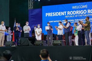 President Rodrigo Roa Duterte shows the copy of Republic Act 11524 or the Coconut Farmers and Industry Trust Fund Act that he received from Senator Cynthia Villar and Representative Alan Peter Cayetano before handing it over to Philippine Coconut Administrator Benjamin Madrigal Jr. during the joint National Task Force-Regional Task Force to End Local Communist Armed Conflict IV-A meeting at the Quezon Convention Center in Lucena City, Quezon on October 21, 2021. KING RODRIGUEZ/ PRESIDENTIAL PHOTO